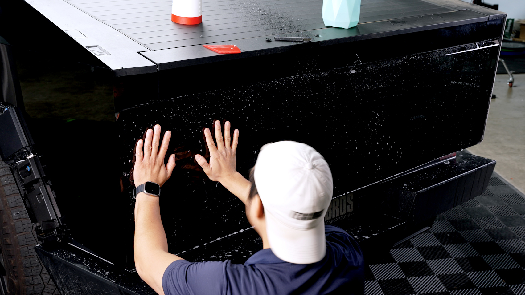 Installer applying a black wrap panel to a vehicle tailgate